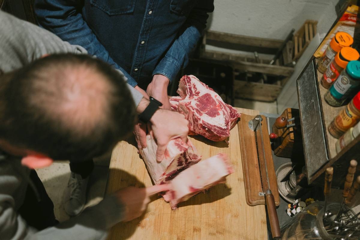 Close-up of hands grinding meat in a stainless steel meat grinder while preparing grinding your own meat recipes